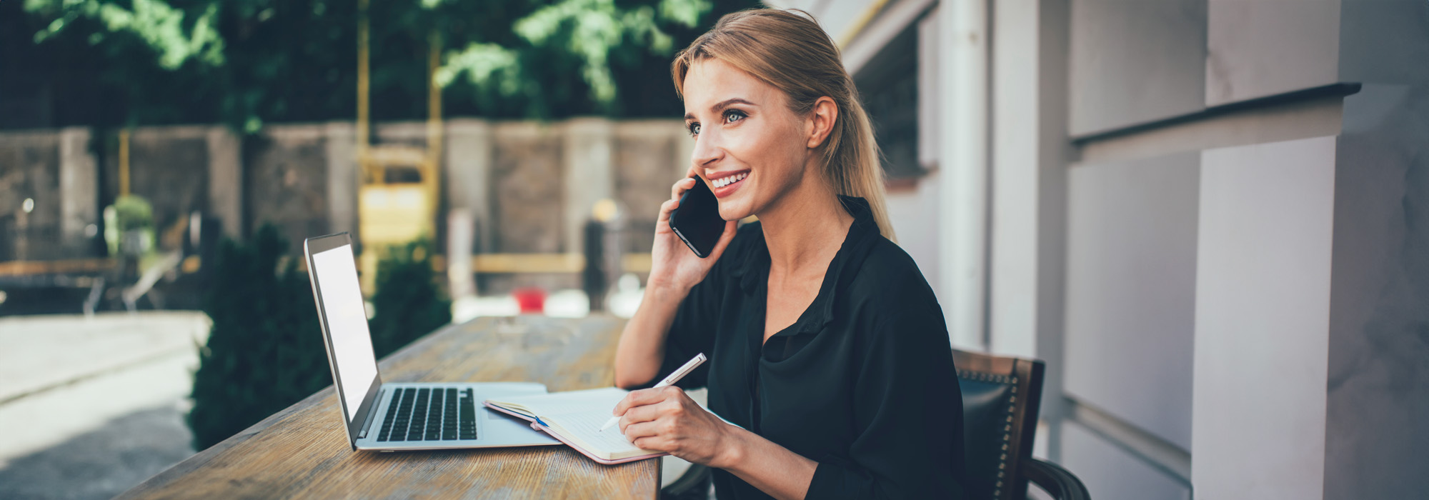 happy female student receiving positive cellphone call sitting outdoors