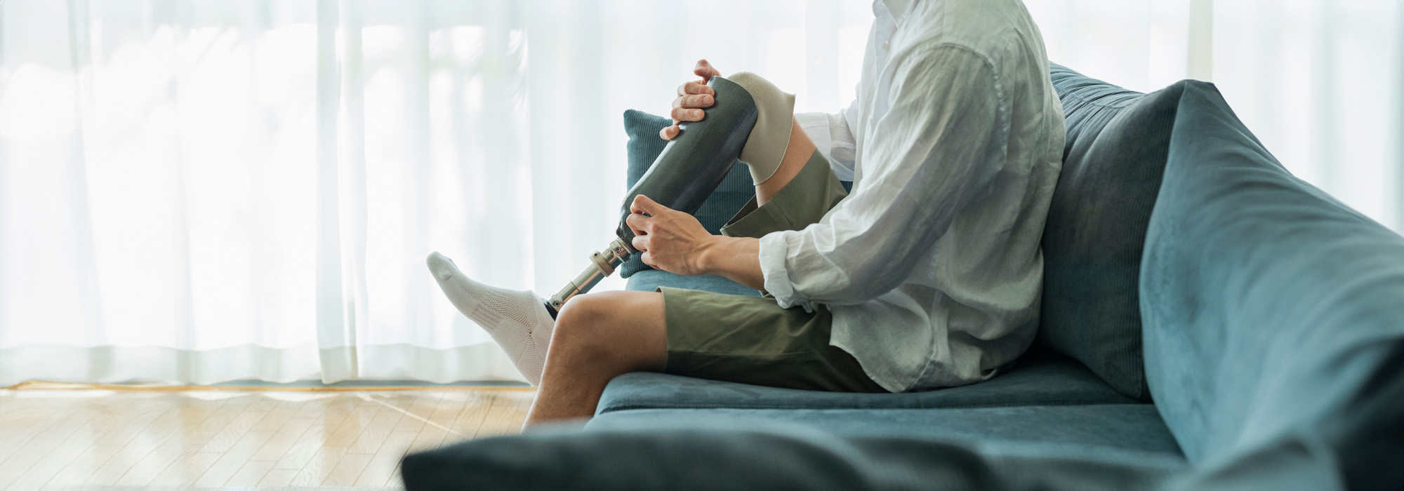 man sitting on couch adjusting prosthetic leg